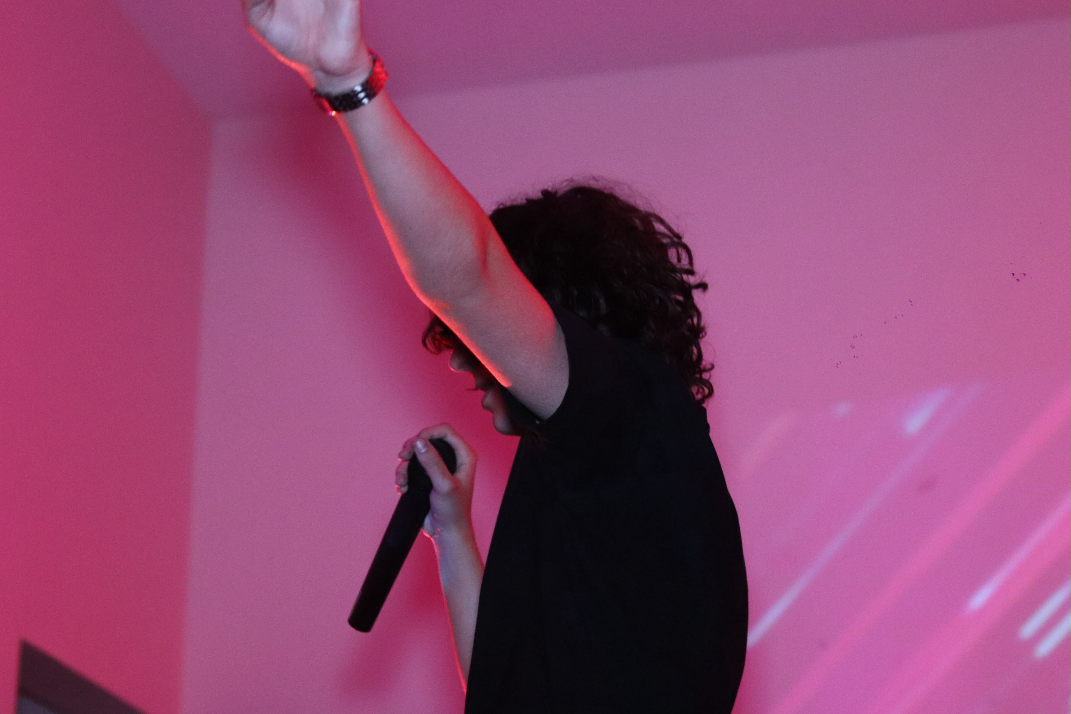 Tennants performing with a microphone under pink lighting